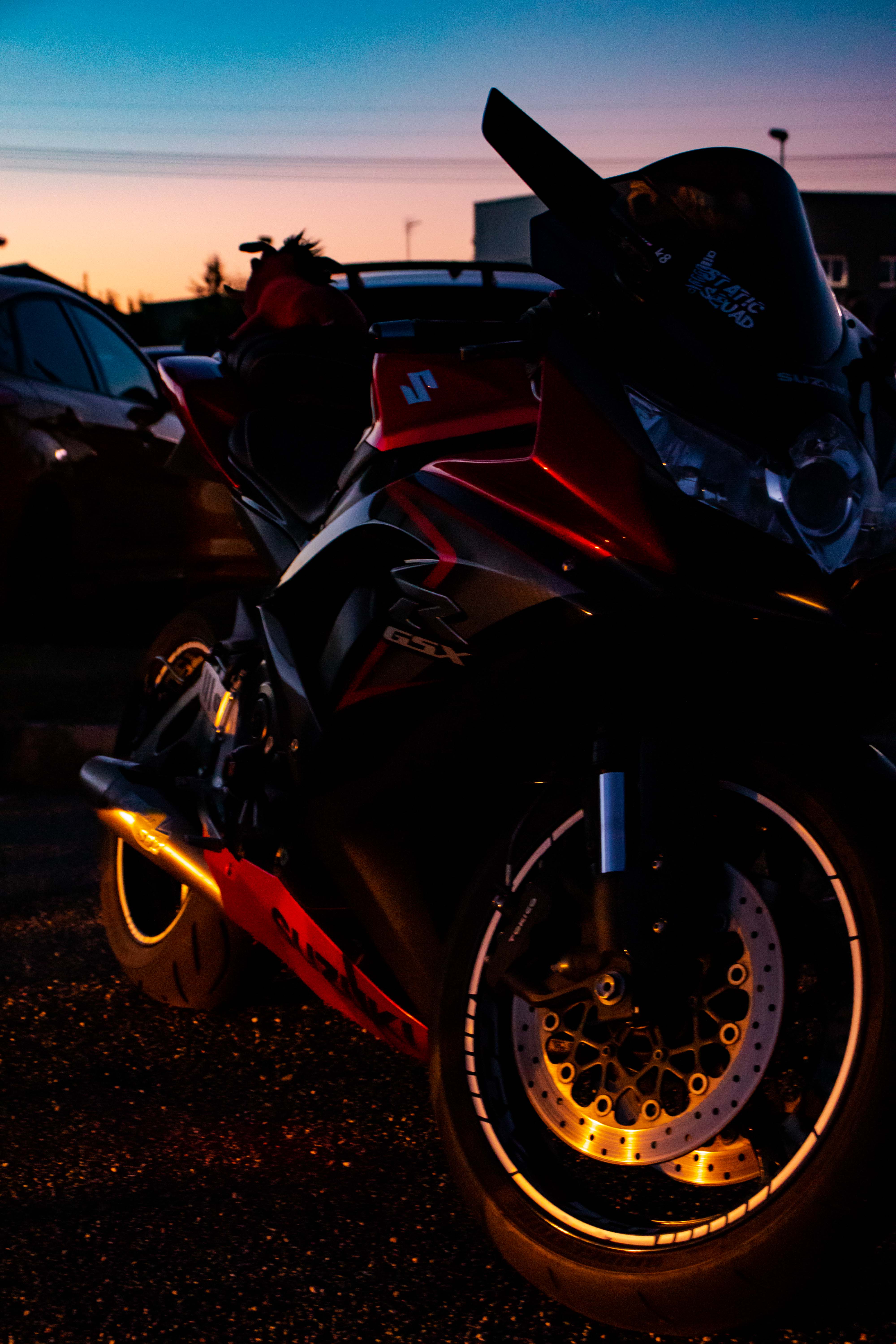 Photo d'une moto rouge avec un reflets lumineux sur la bas vu trois quart face
